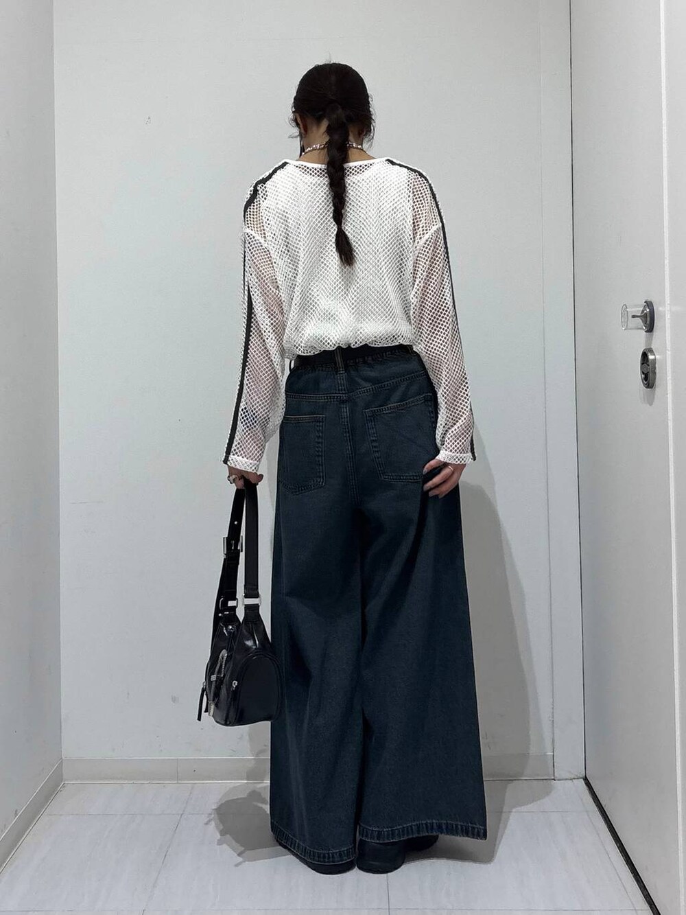 ブルー系のデニムパンツ、ブラック系のスニーカー、ホワイト系のTシャツ/カットソーを着用したレディースの春コーディネートの5枚目の写真