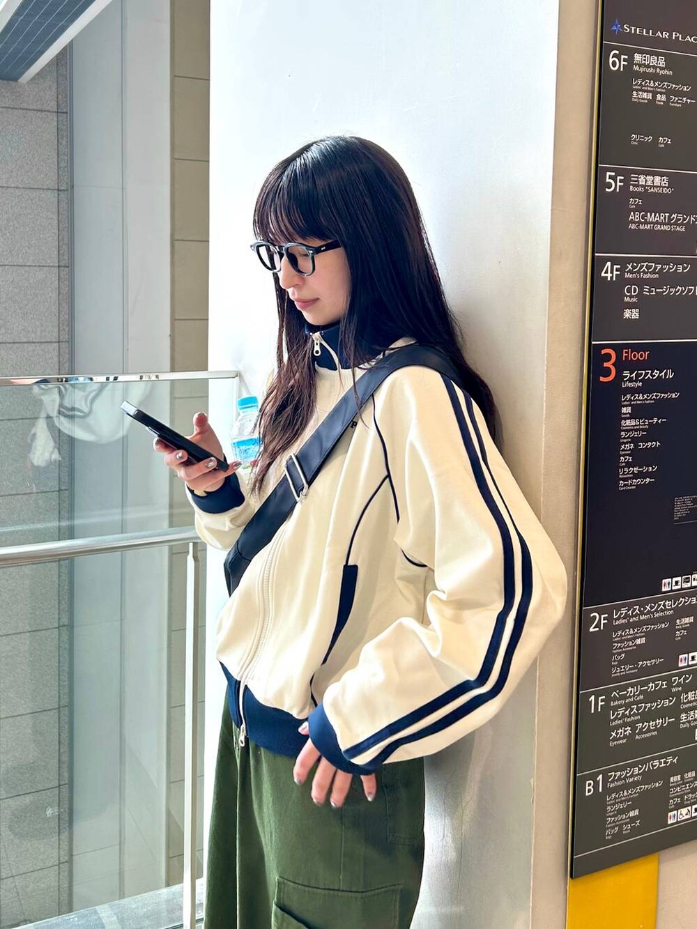 ホワイト系のセットアップ、ブラック系のショルダーバッグ、グリーン系のその他パンツを着用したレディースの春コーディネートの4枚目の写真