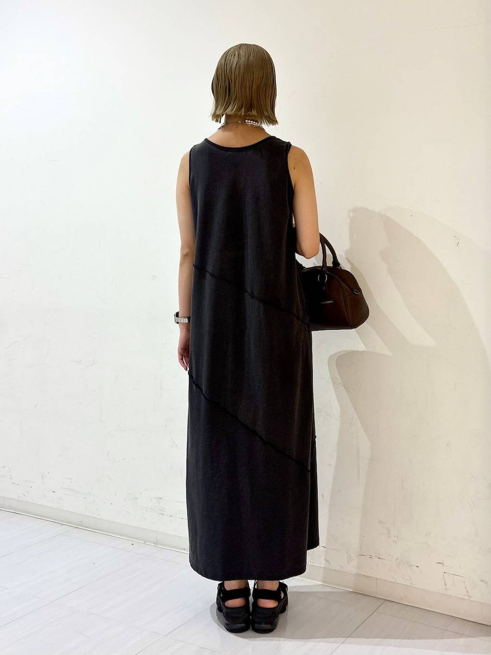 ブラック系のワンピース、ブラウン系のショルダーバッグ、ホワイト系のネックレスを着用したレディースの夏コーディネートの5枚目の写真