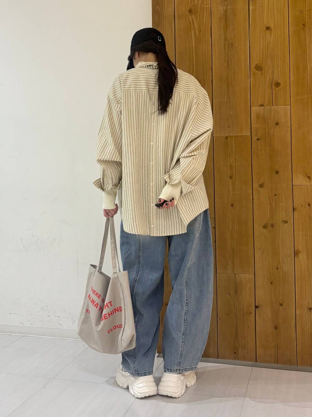 ホワイト系のスニーカー、ベージュ系のトートバッグ、ブルー系のデニムパンツを着用したレディースの冬コーディネートの4枚目の写真