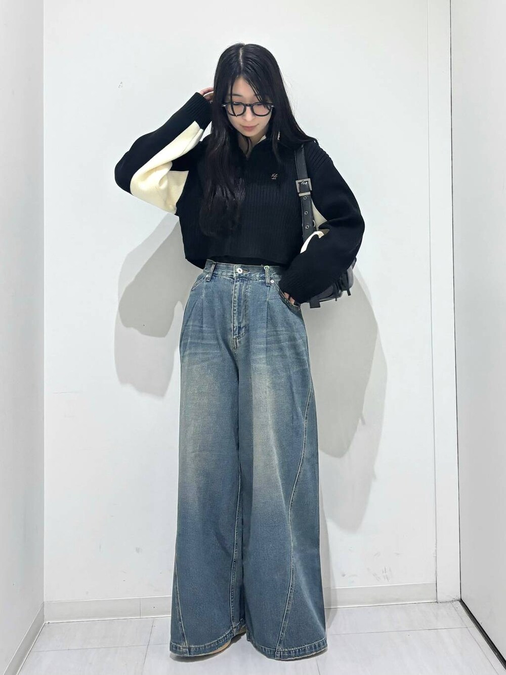 ブルー系のデニムパンツ、ブラック系のショルダーバッグ、ブラック系のニット/セーターを着用したレディースの秋コーディネートの5枚目の写真