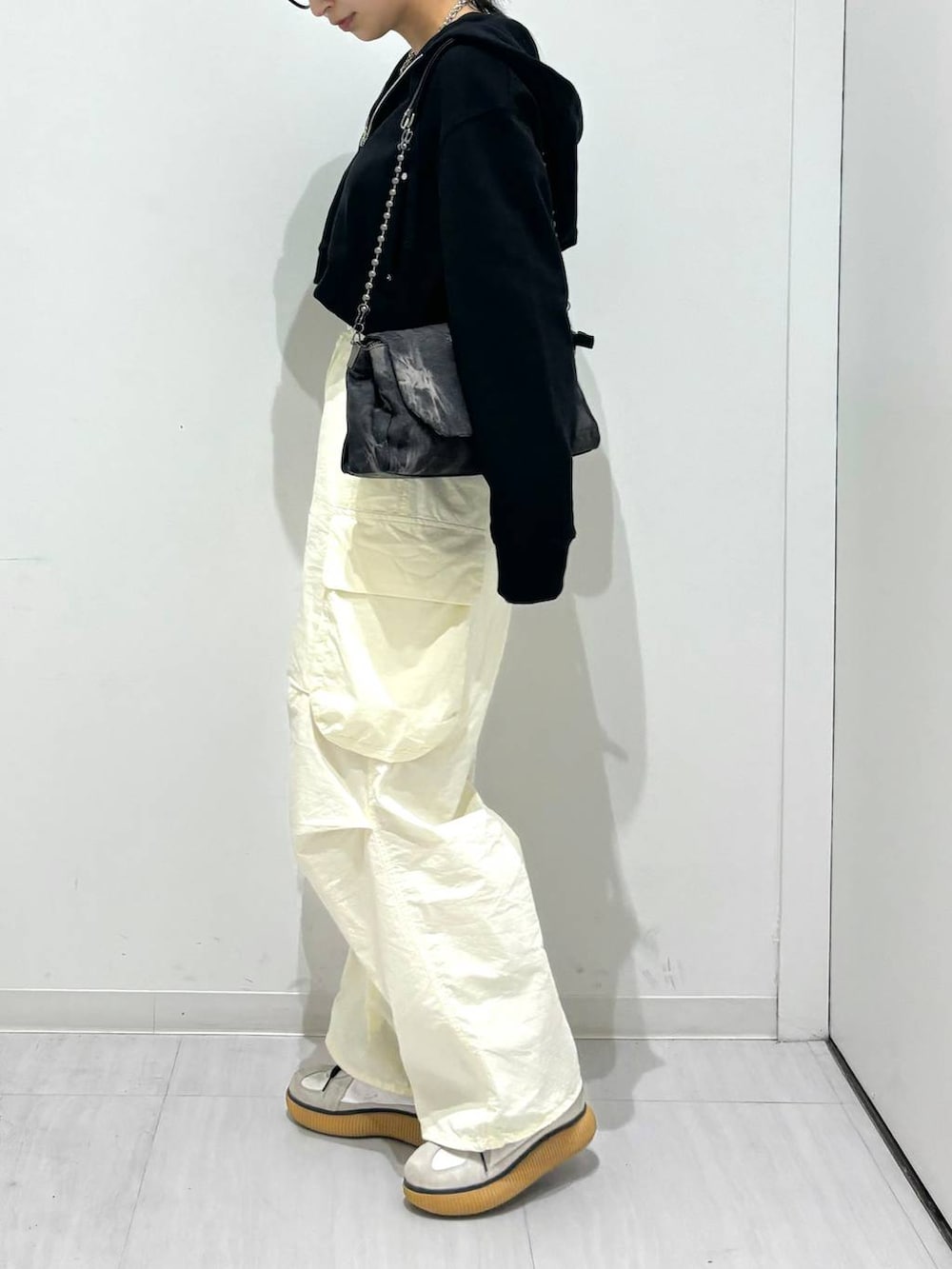 ブラック系のパーカー、ブラック系のショルダーバッグ、ホワイト系のカーゴパンツを着用したレディースの春コーディネートの3枚目の写真