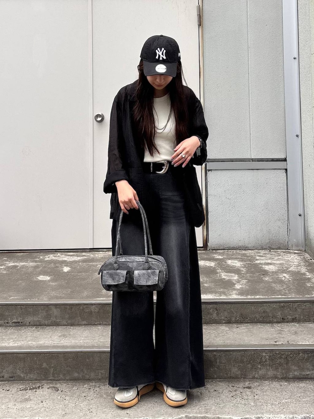 ブラック系のボストンバッグ、ホワイト系のタンクトップ、ブラック系のデニムパンツを着用したレディースの春コーディネートの7枚目の写真