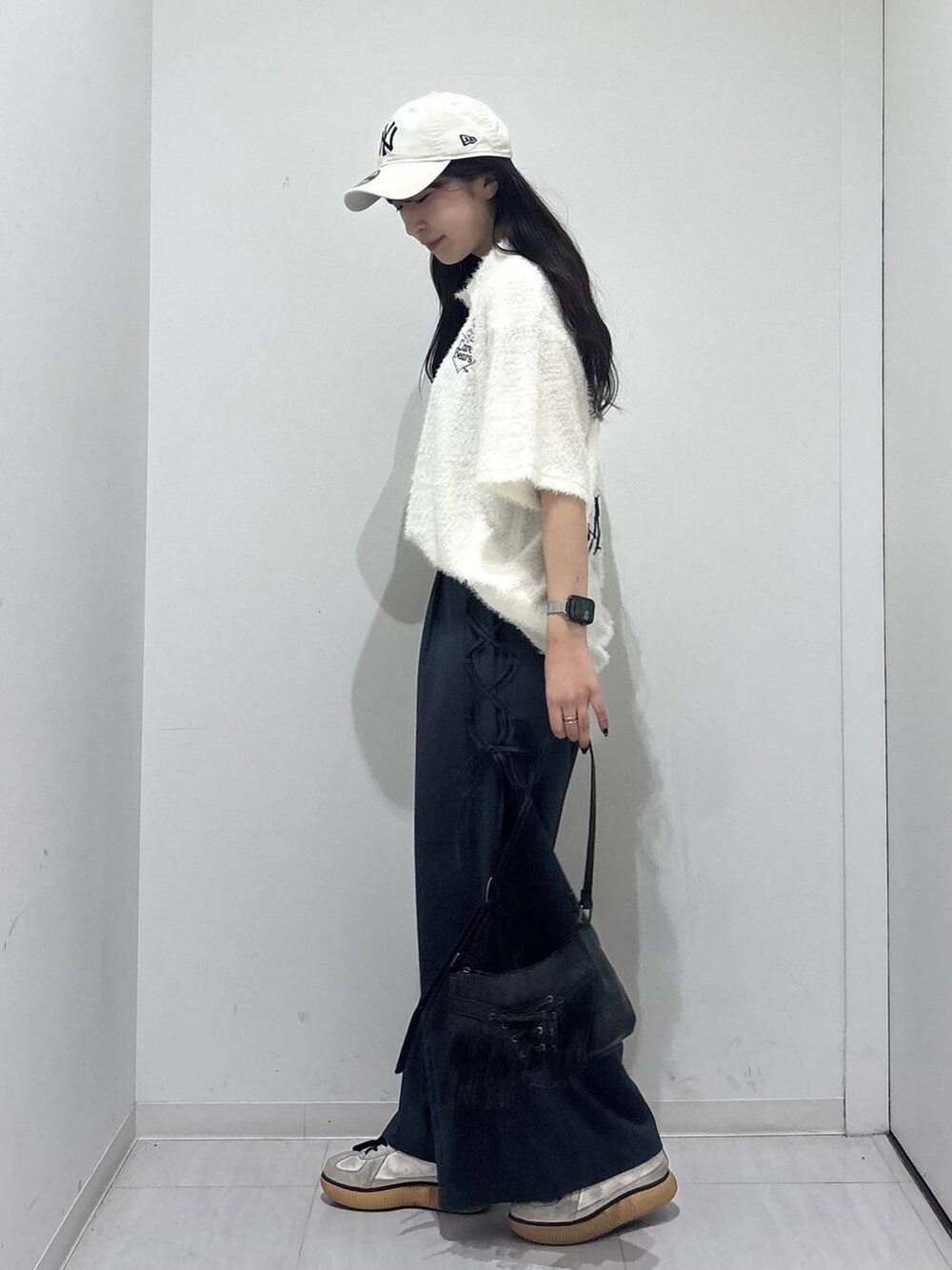 ブラック系のショルダーバッグ、グレー系のスラックス、ホワイト系のポロシャツを着用したレディースの春コーディネートの6枚目の写真