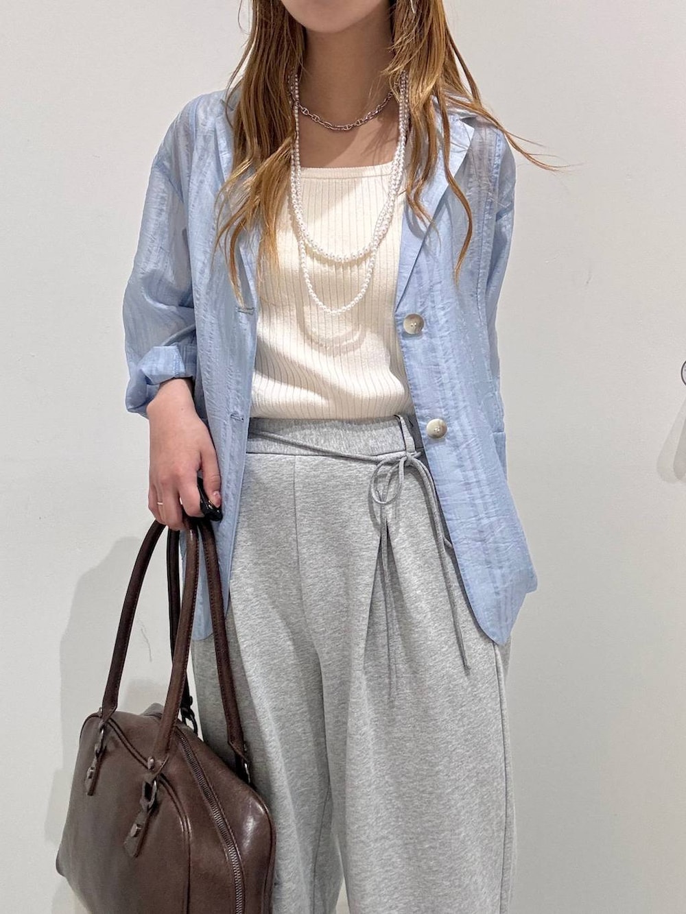 ブラウン系のボストンバッグ、ホワイト系のタンクトップ、ブルー系のテーラードジャケットを着用したレディースの春コーディネートの3枚目の写真