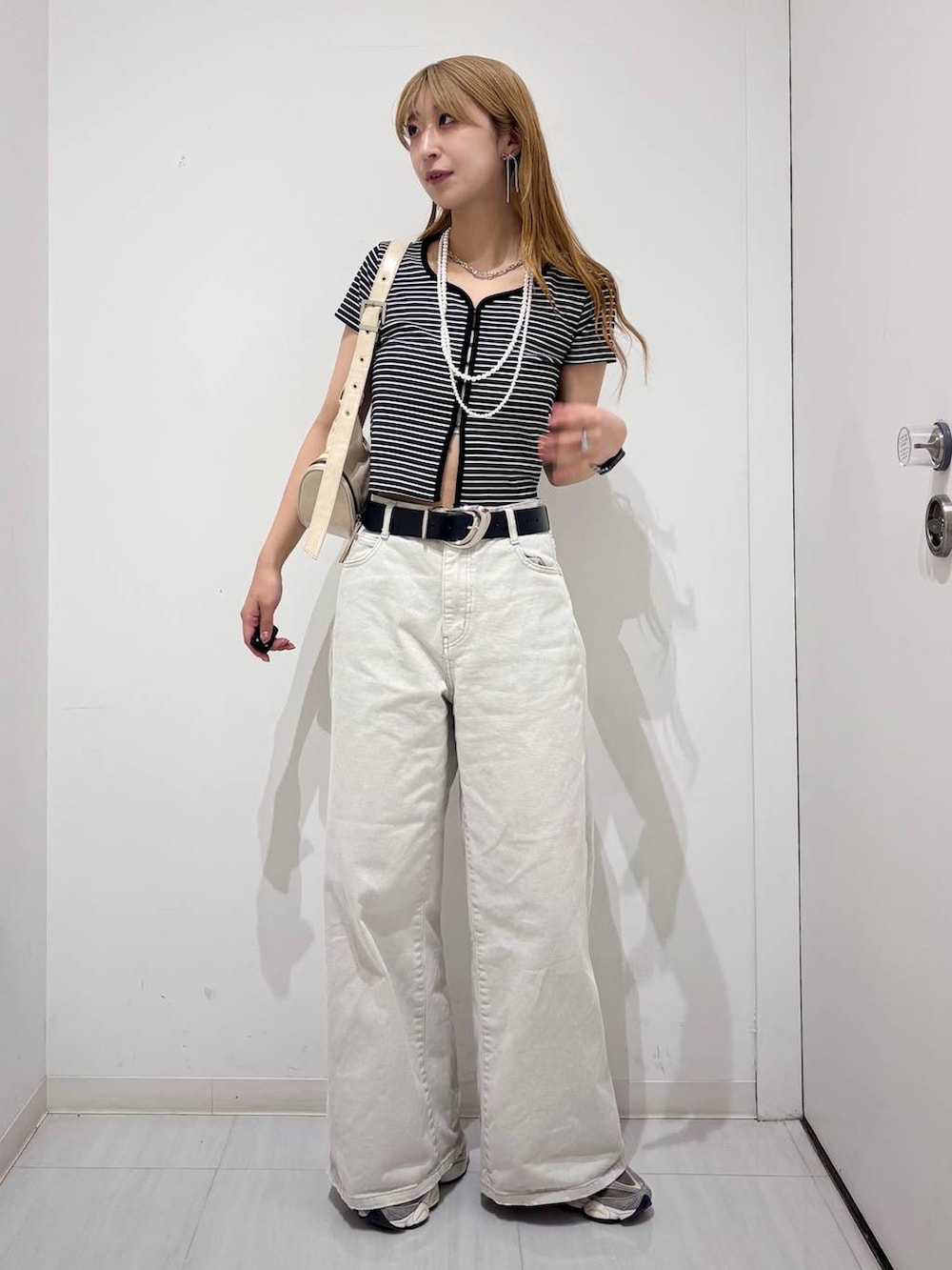 グレー系のデニムパンツ、ホワイト系のショルダーバッグ、ブラック系のTシャツ/カットソーを着用したレディースの春コーディネートの8枚目の写真