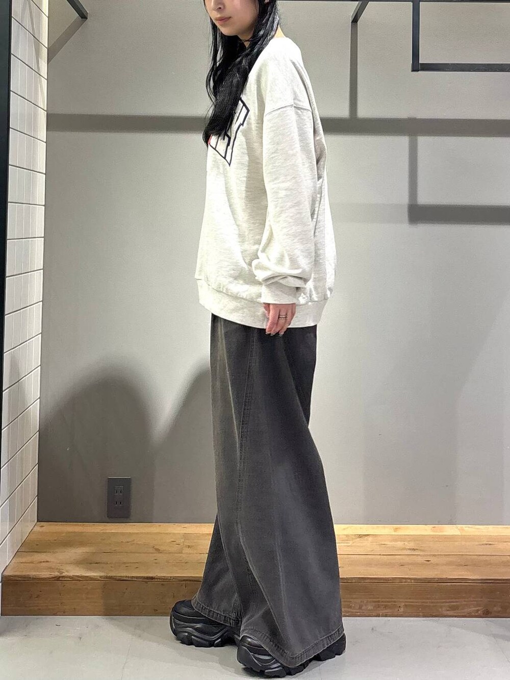 ブラック系のデニムパンツ、ベージュ系のスウェット、ブラック系のブーツを着用したレディースの秋コーディネートの3枚目の写真