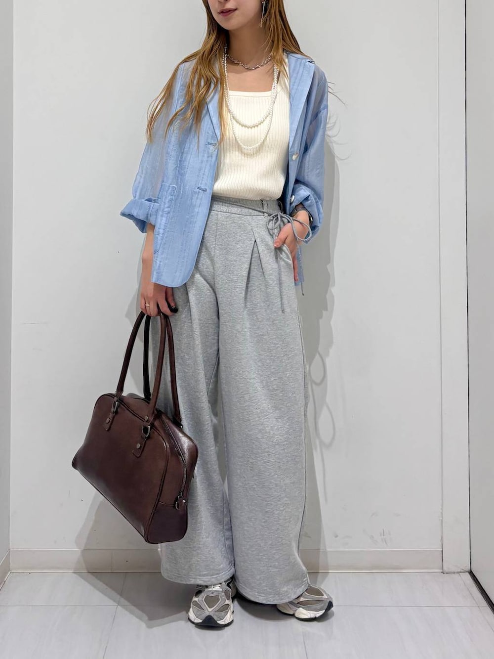 ブラウン系のボストンバッグ、ホワイト系のタンクトップ、ブルー系のテーラードジャケットを着用したレディースの春コーディネートの5枚目の写真