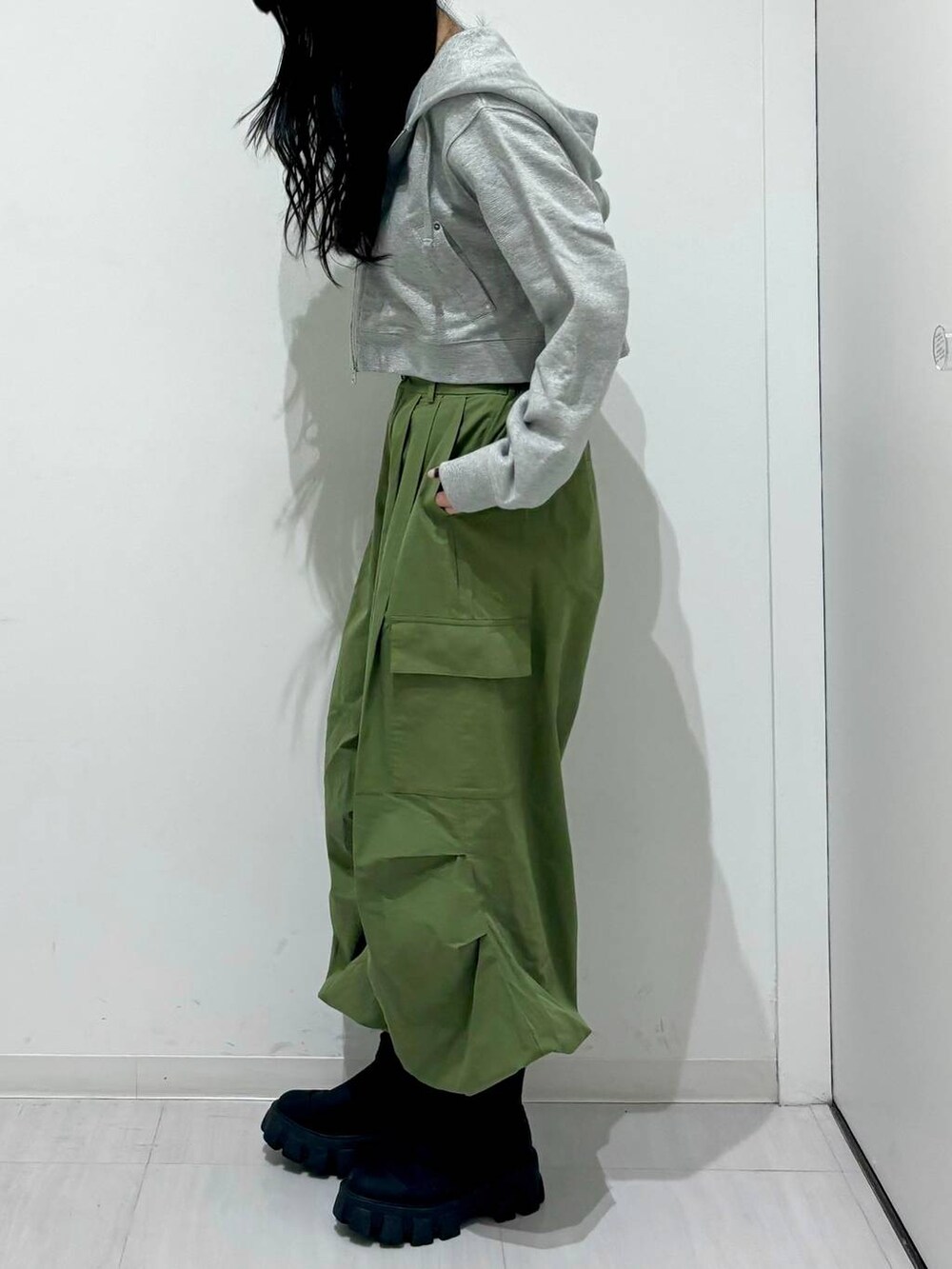 グレー系のパーカー、ブラック系のブーツ、グリーン系のその他パンツを着用したレディースの冬コーディネートの3枚目の写真