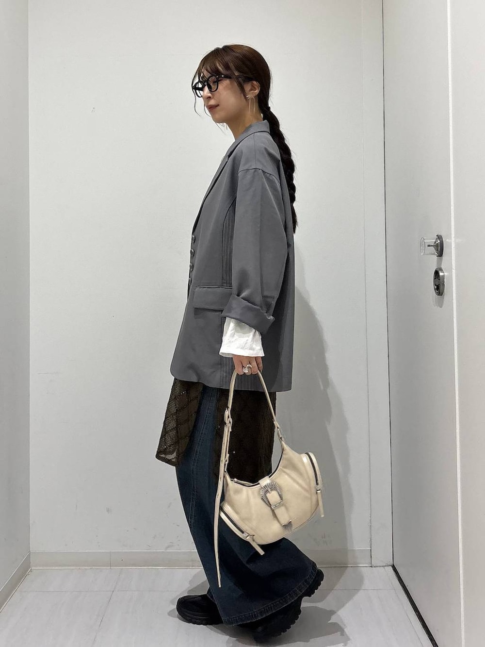 ブルー系のデニムパンツ、ブラック系のスニーカー、ホワイト系のショルダーバッグを着用したレディースの春コーディネートの5枚目の写真