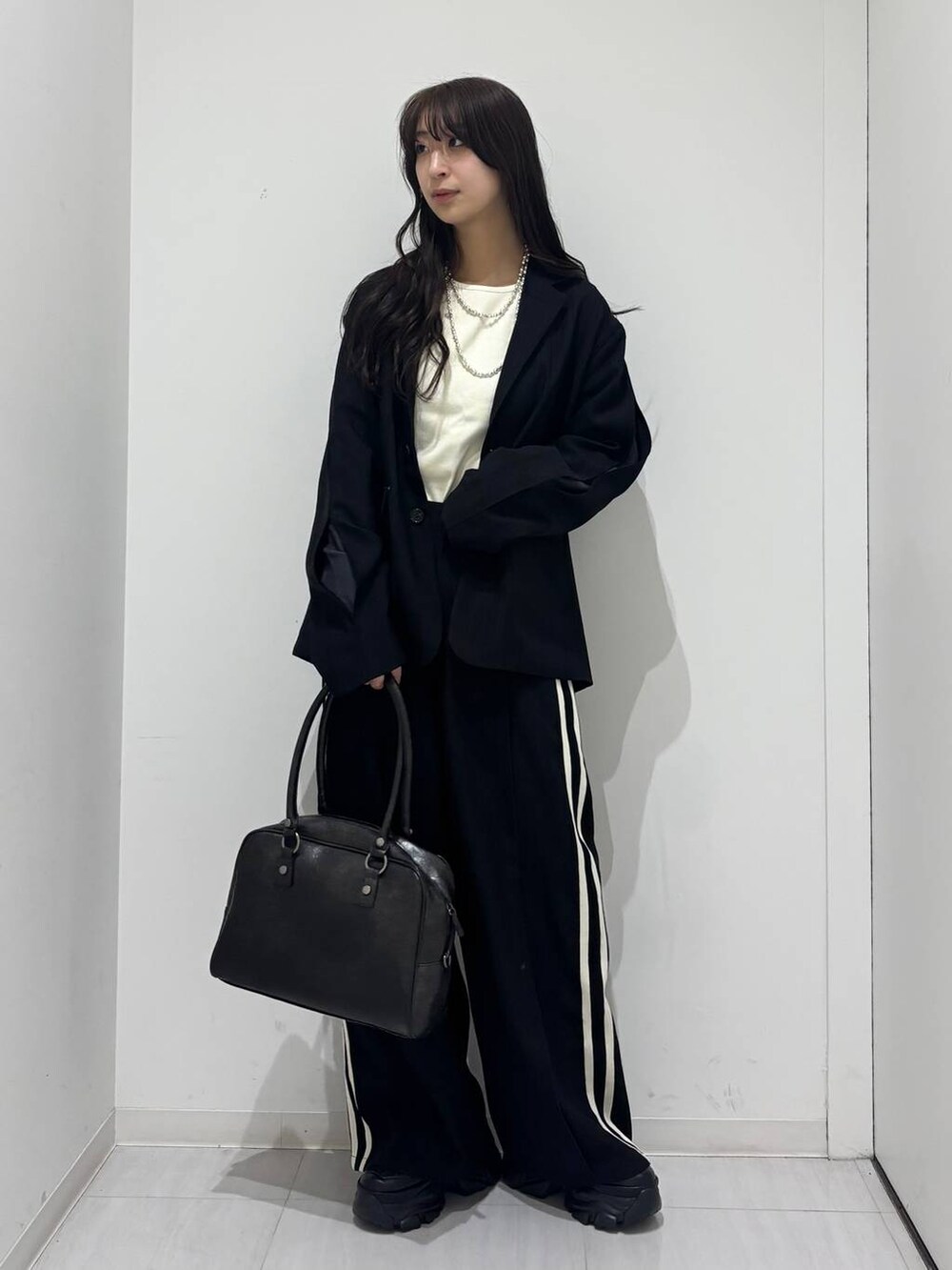ブラック系のスニーカー、ブラック系のボストンバッグ、ブラック系のテーラードジャケットを着用したレディースの冬コーディネートの5枚目の写真