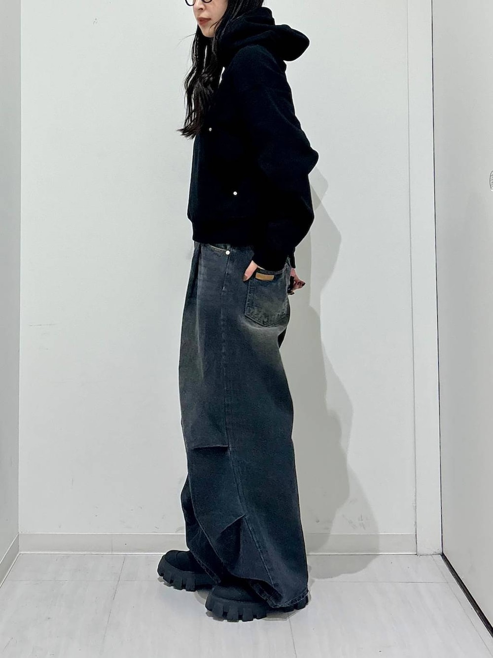 ブラック系のパーカー、ブラック系のブーツ、ブラック系のデニムパンツを着用したレディースの冬コーディネートの3枚目の写真