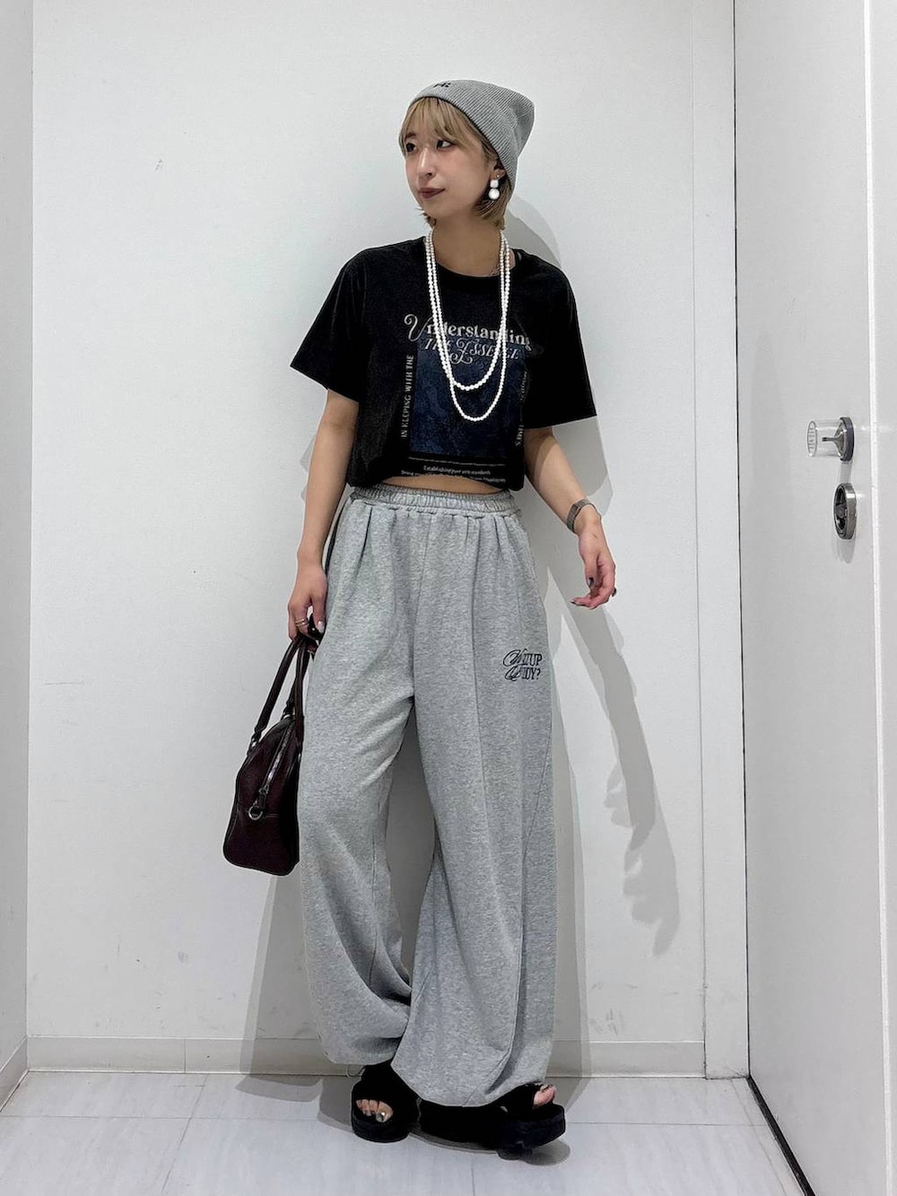 ブラウン系のショルダーバッグ、グレー系のスウェットパンツ、グレー系のTシャツ/カットソーを着用したレディースの夏コーディネートの2枚目の写真