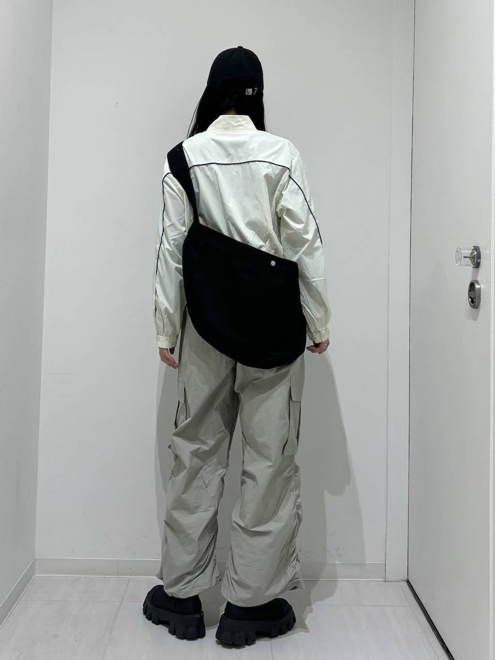 ホワイト系のブルゾン、グレー系のカーゴパンツ、ブラック系のショルダーバッグを着用したレディースの春コーディネートの3枚目の写真