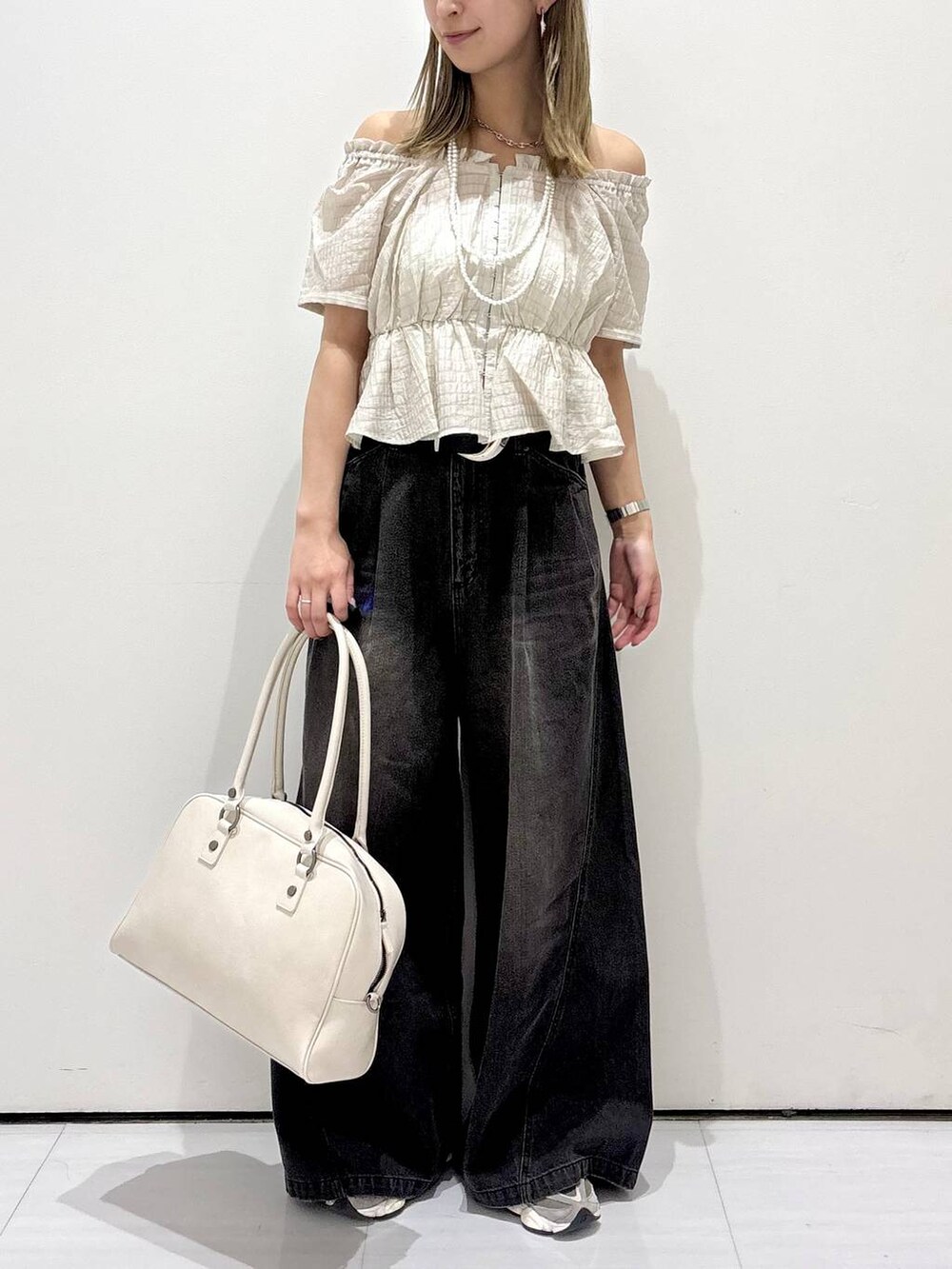 ブラック系のデニムパンツ、ホワイト系のボストンバッグ、ホワイト系のネックレスを着用したレディースの夏コーディネートの2枚目の写真