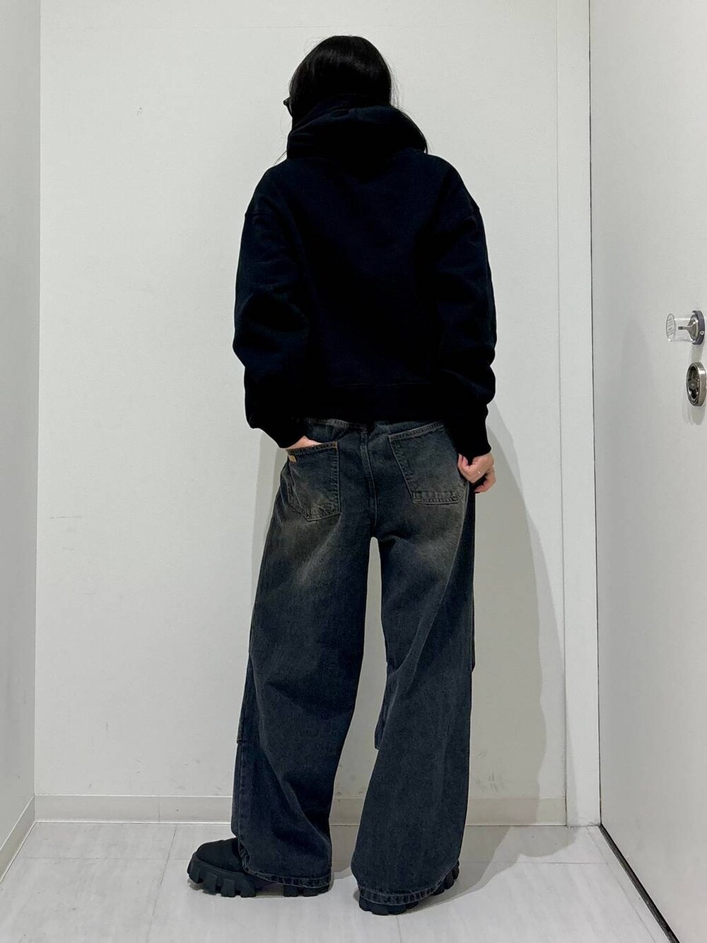 ブラック系のパーカー、ブラック系のブーツ、ブラック系のデニムパンツを着用したレディースの冬コーディネートの5枚目の写真