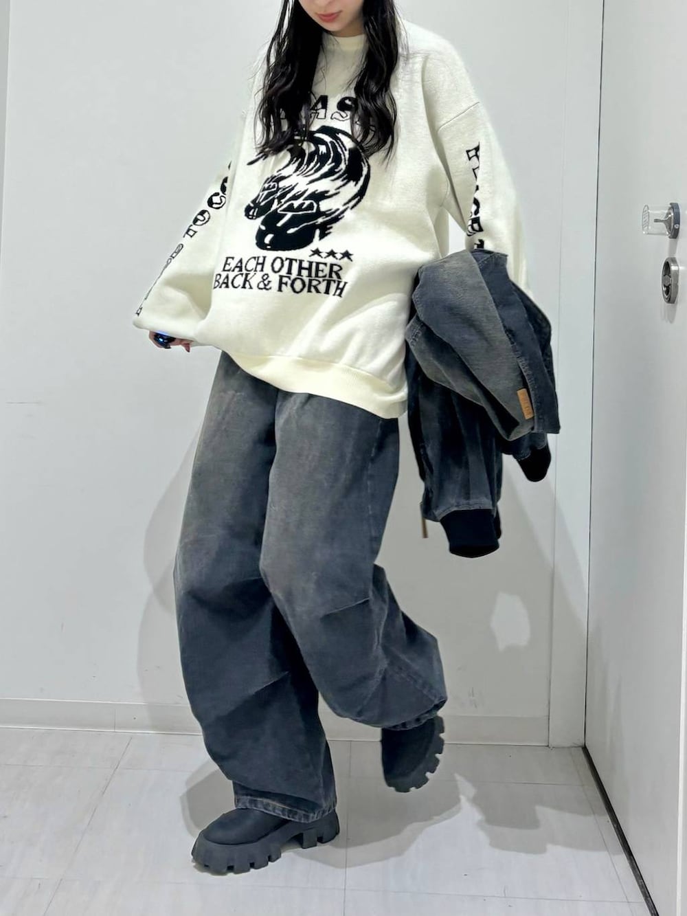 ホワイト系のニット/セーター、ブラック系のデニムジャケット、ブラック系のブーツを着用したレディースの冬コーディネートの3枚目の写真