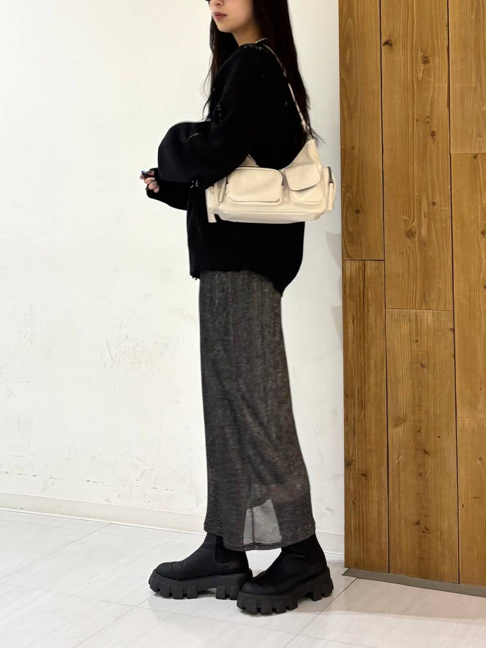 ホワイト系のショルダーバッグ、ブラック系のニット/セーター、ブラック系のスカートを着用したレディースの冬コーディネートの3枚目の写真