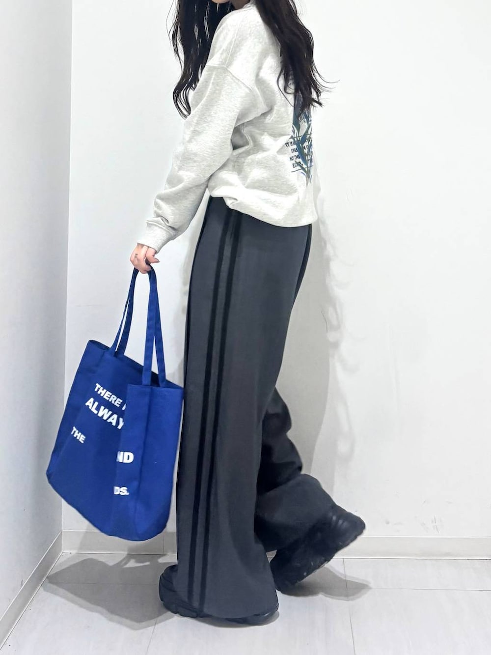 グレー系のスウェット、グレー系のスラックス、ブルー系のトートバッグを着用したレディースの冬コーディネートの4枚目の写真