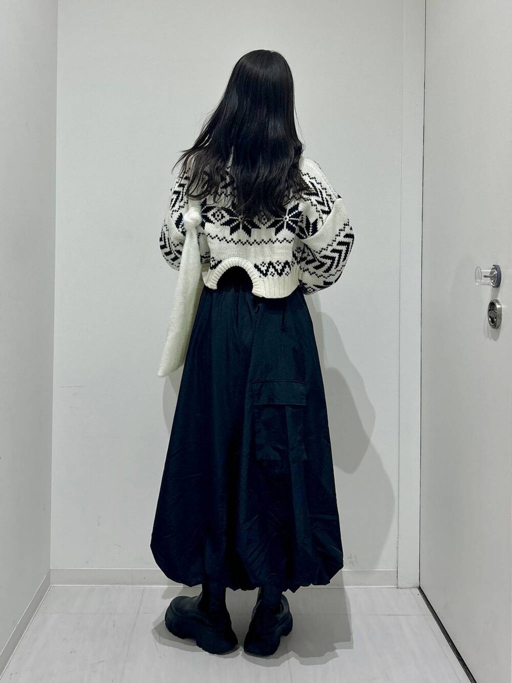 ブラック系のブーツ、ホワイト系のニット/セーター、ブラック系のスカートを着用したレディースの冬コーディネートの3枚目の写真