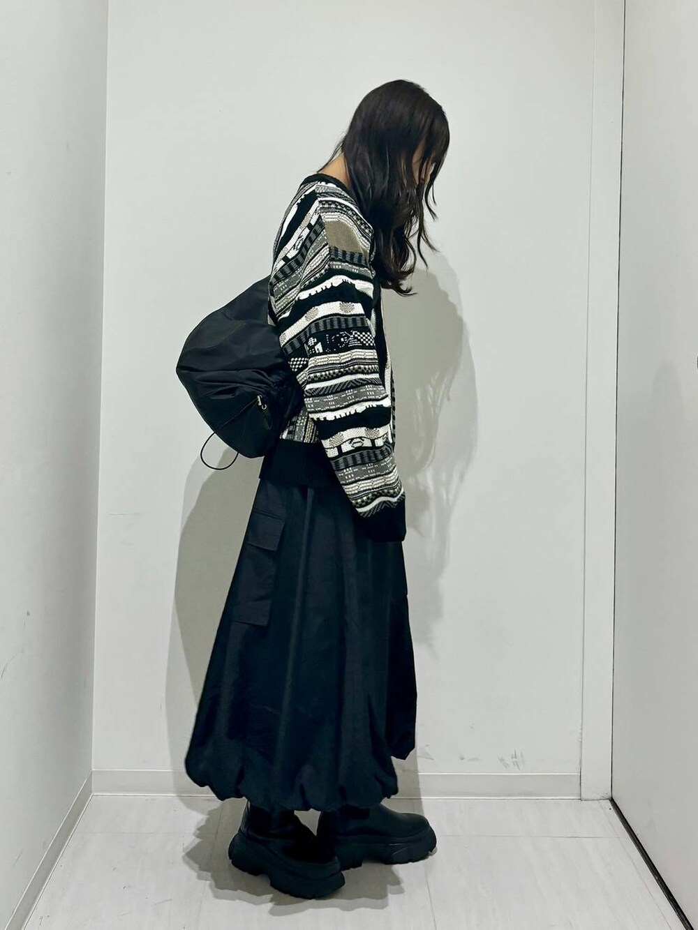 ブラック系のブーツ、ブラック系のショルダーバッグ、ブラック系のニット/セーターを着用したレディースの秋コーディネートの3枚目の写真