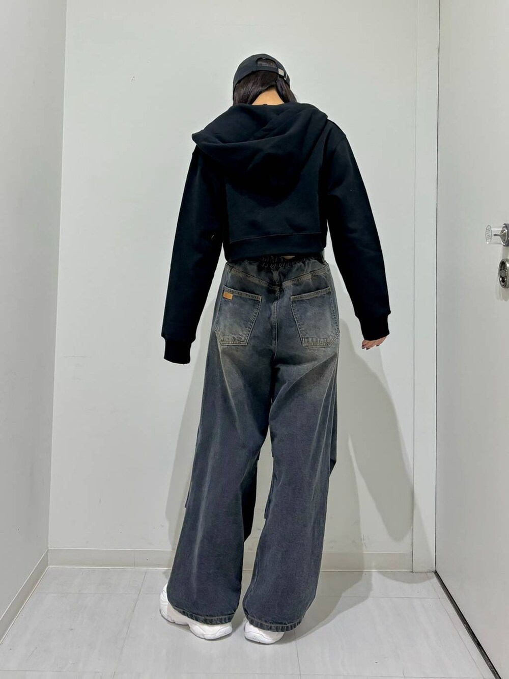 ブラック系のパーカー、ブラック系のデニムパンツ、ホワイト系のスニーカーを着用したレディースの冬コーディネートの3枚目の写真