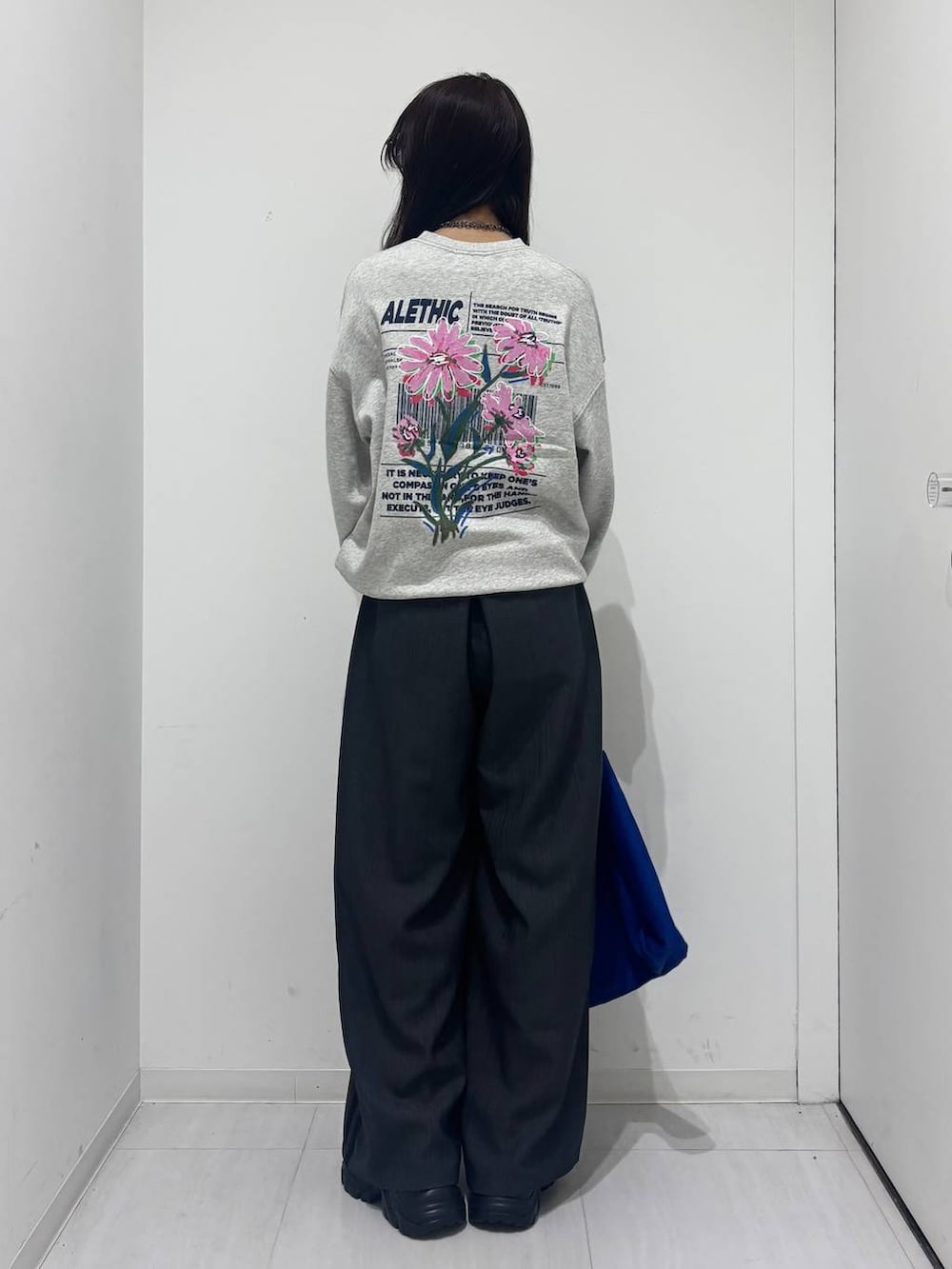 グレー系のスウェット、グレー系のスラックス、ブルー系のトートバッグを着用したレディースの冬コーディネートの3枚目の写真