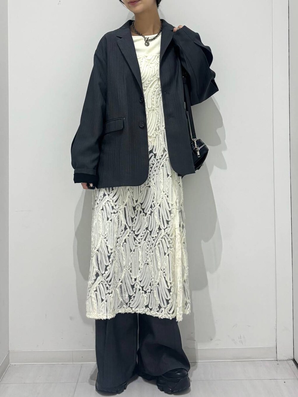 ブラック系のスニーカー、ホワイト系のワンピース、ブラック系のショルダーバッグを着用したレディースの冬コーディネートの2枚目の写真