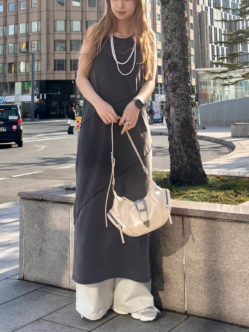 グレー系のデニムパンツ、ホワイト系のショルダーバッグ、ブラック系のワンピースを着用したレディースの春コーディネートの6枚目の写真