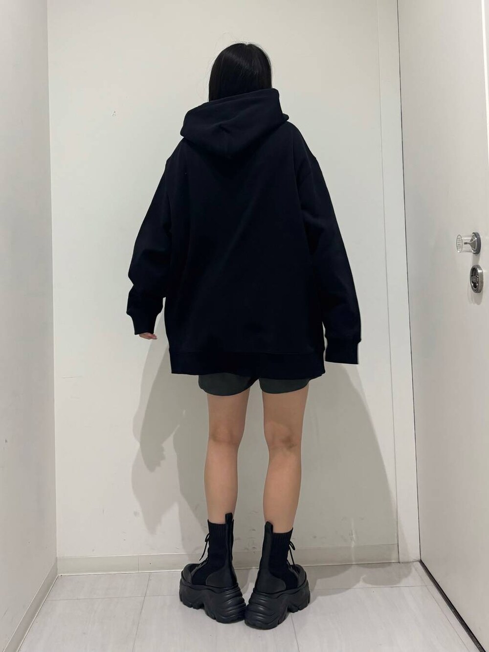 ブラック系のブーツ、ブラック系のパーカー、グレー系のその他パンツを着用したレディースの秋コーディネートの5枚目の写真