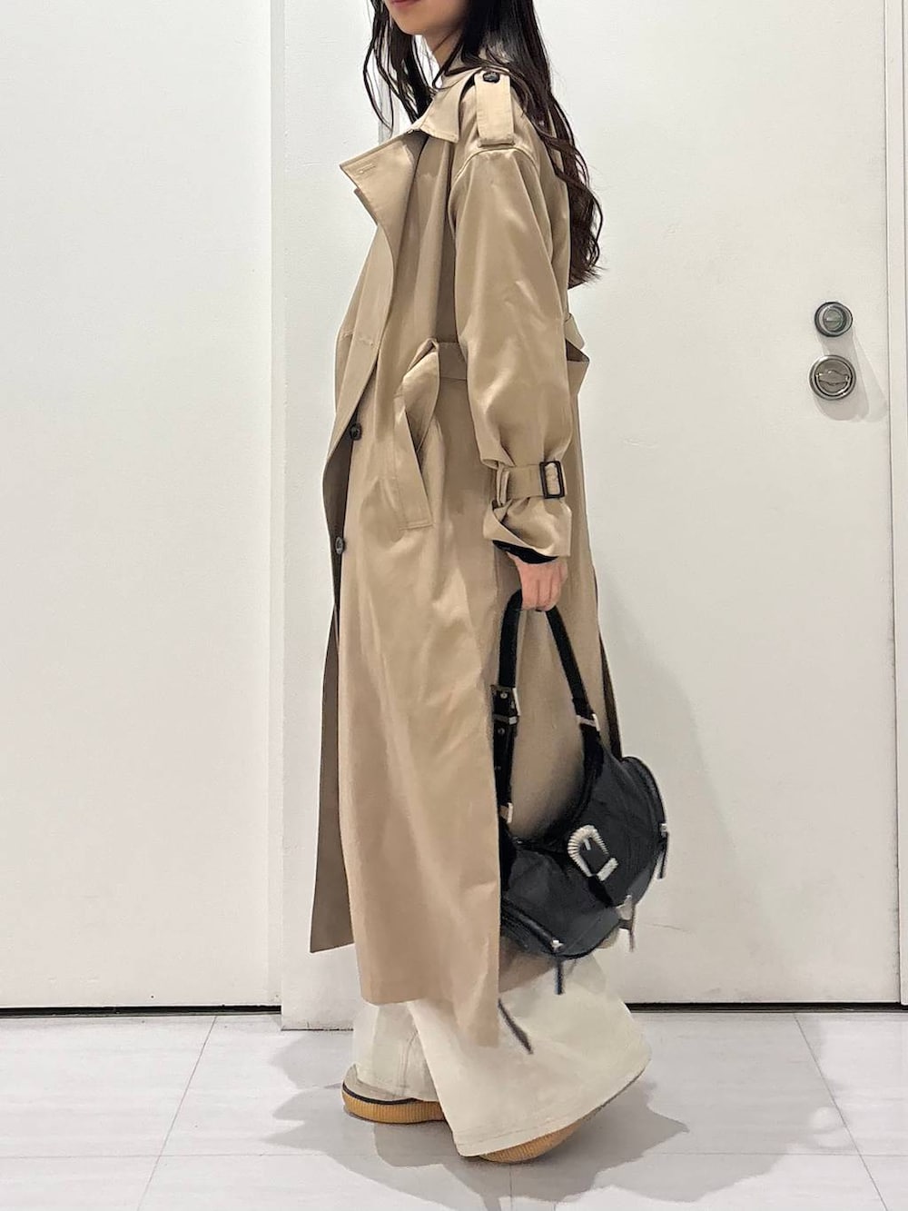 グレー系のデニムパンツ、ベージュ系のトレンチコート、ブラック系のショルダーバッグを着用したレディースの春コーディネートの4枚目の写真