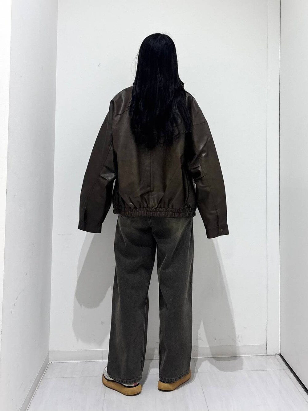 ブラウン系のブルゾン、ブラック系のデニムパンツ、ブラック系のニット/セーターを着用したレディースの秋コーディネートの3枚目の写真