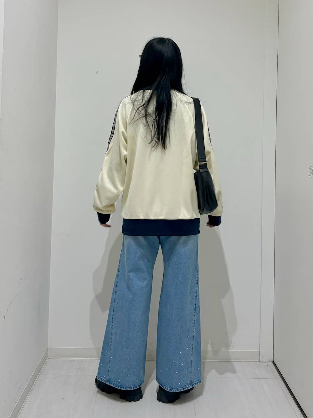 ホワイト系のセットアップ、ブラック系のブーツ、ブラック系のショルダーバッグを着用したレディースの冬コーディネートの3枚目の写真