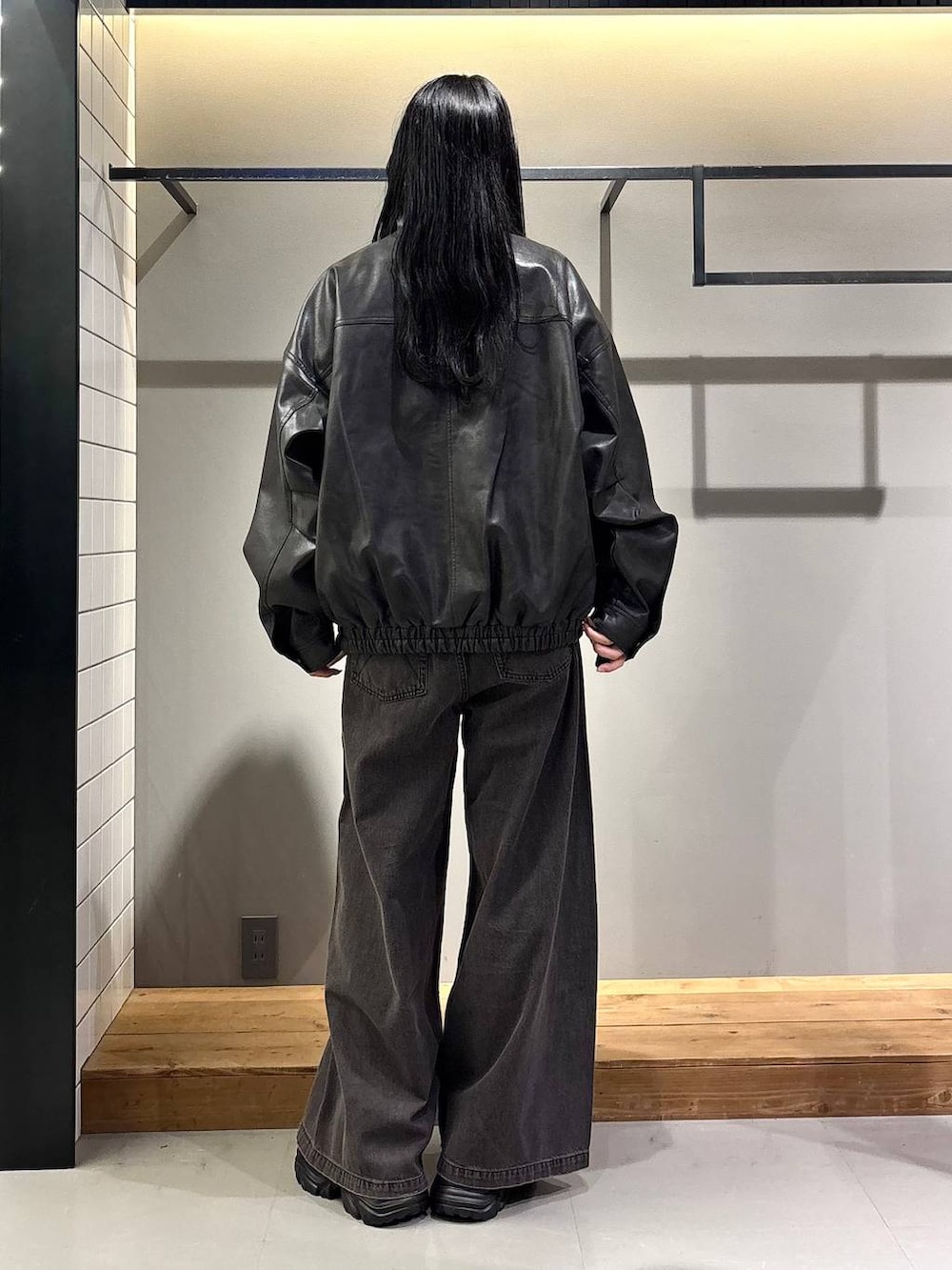 ブラック系のデニムパンツ、ブラック系のブルゾン、ブラック系のブーツを着用したレディースの秋コーディネートの5枚目の写真