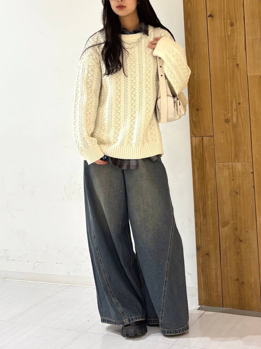 ブルー系のデニムパンツ、ホワイト系のショルダーバッグ、ホワイト系のニット/セーターを着用したレディースの冬コーディネートの4枚目の写真