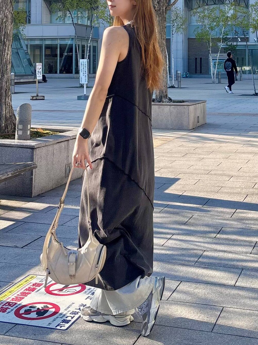 グレー系のデニムパンツ、ホワイト系のショルダーバッグ、ブラック系のワンピースを着用したレディースの春コーディネートの3枚目の写真