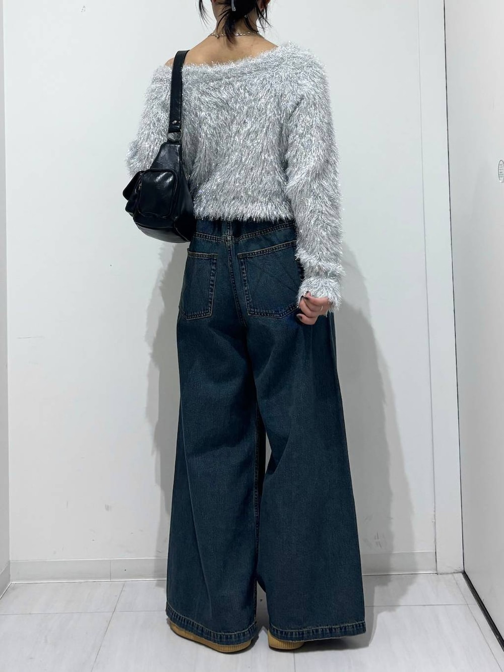 ブルー系のデニムパンツ、ブラック系のショルダーバッグ、ホワイト系のニット/セーターを着用したレディースの秋コーディネートの4枚目の写真