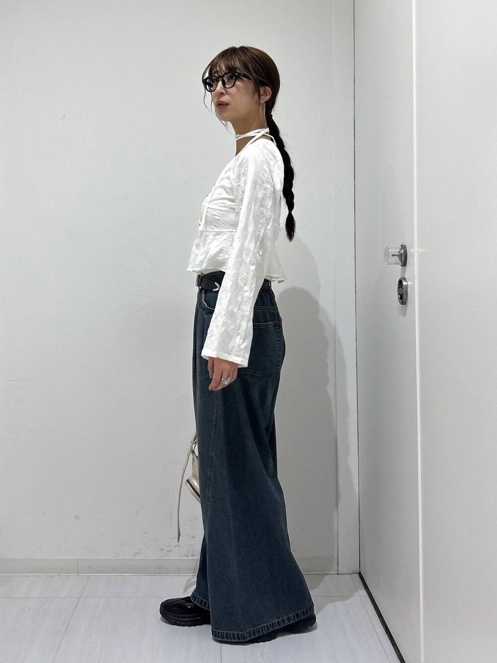 ブルー系のデニムパンツ、ブラック系のスニーカー、ホワイト系のショルダーバッグを着用したレディースの春コーディネートの4枚目の写真
