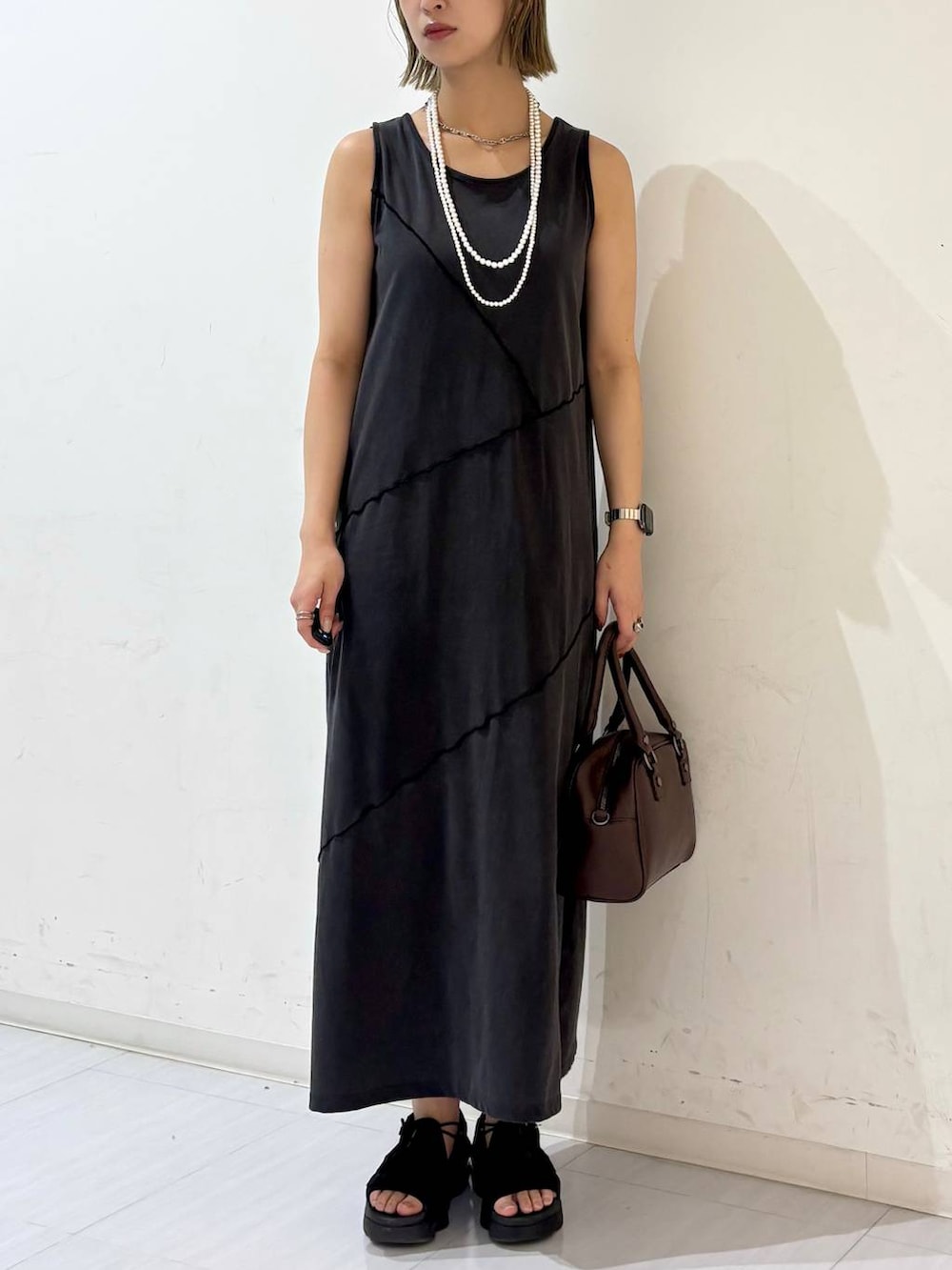ブラック系のワンピース、ブラウン系のショルダーバッグ、ホワイト系のネックレスを着用したレディースの夏コーディネートの6枚目の写真