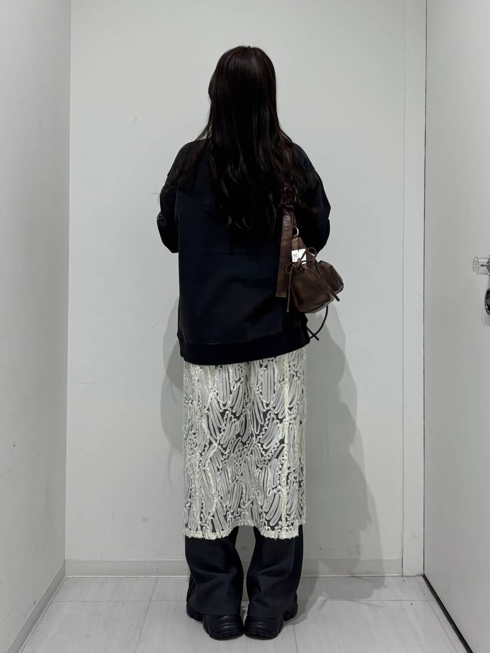 ブラック系のスニーカー、グレー系のスウェット、ブラウン系のショルダーバッグを着用したレディースの冬コーディネートの3枚目の写真