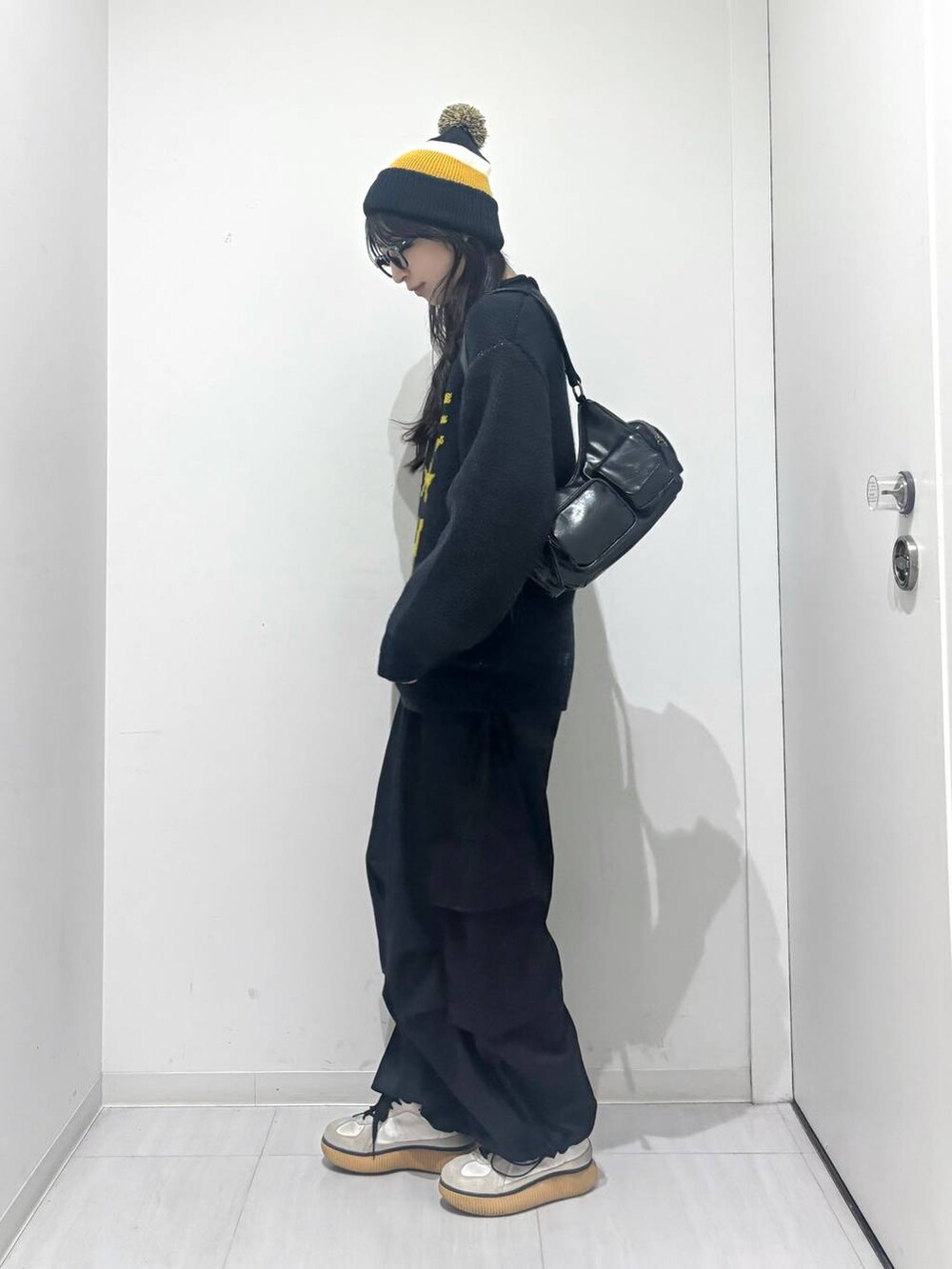 ブラック系のショルダーバッグ、ブラック系のカーゴパンツ、ブルー系のニット/セーターを着用したレディースの秋コーディネートの3枚目の写真