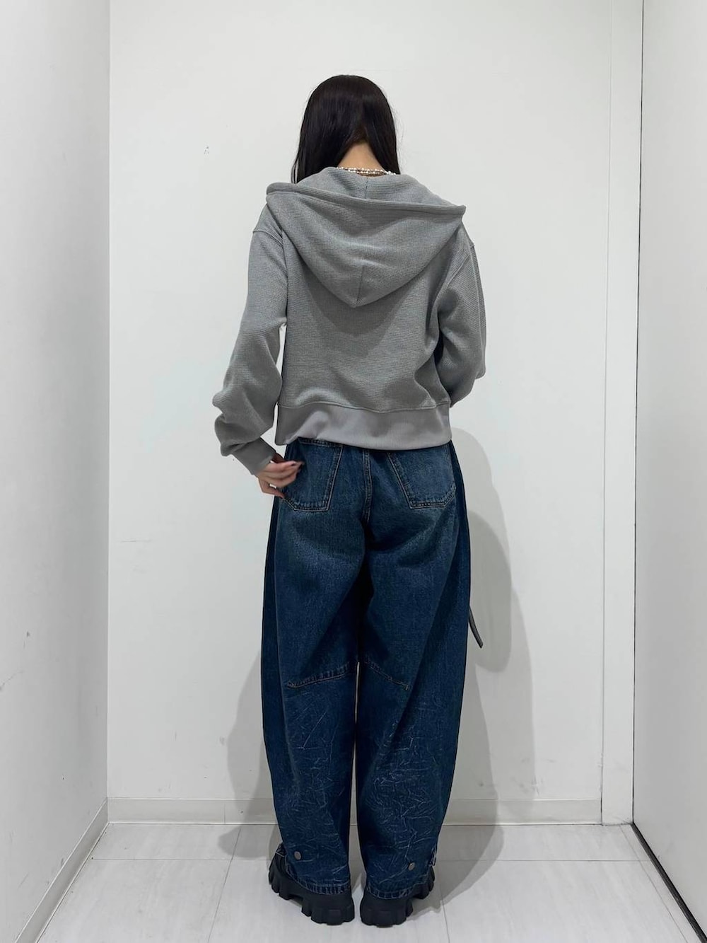 ブルー系のデニムパンツ、グレー系のパーカー、ブラック系のベルトを着用したレディースの冬コーディネートの4枚目の写真