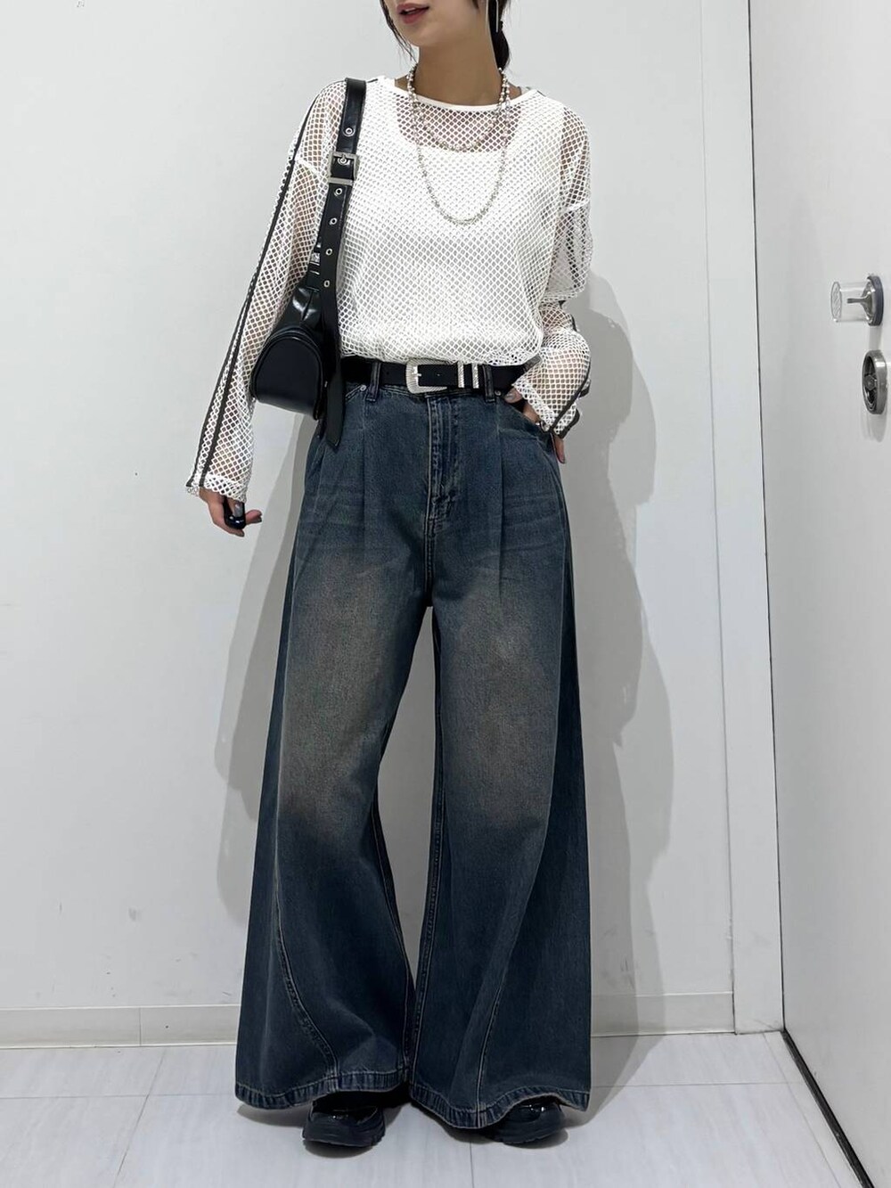 ブルー系のデニムパンツ、ブラック系のスニーカー、ホワイト系のTシャツ/カットソーを着用したレディースの春コーディネートの6枚目の写真