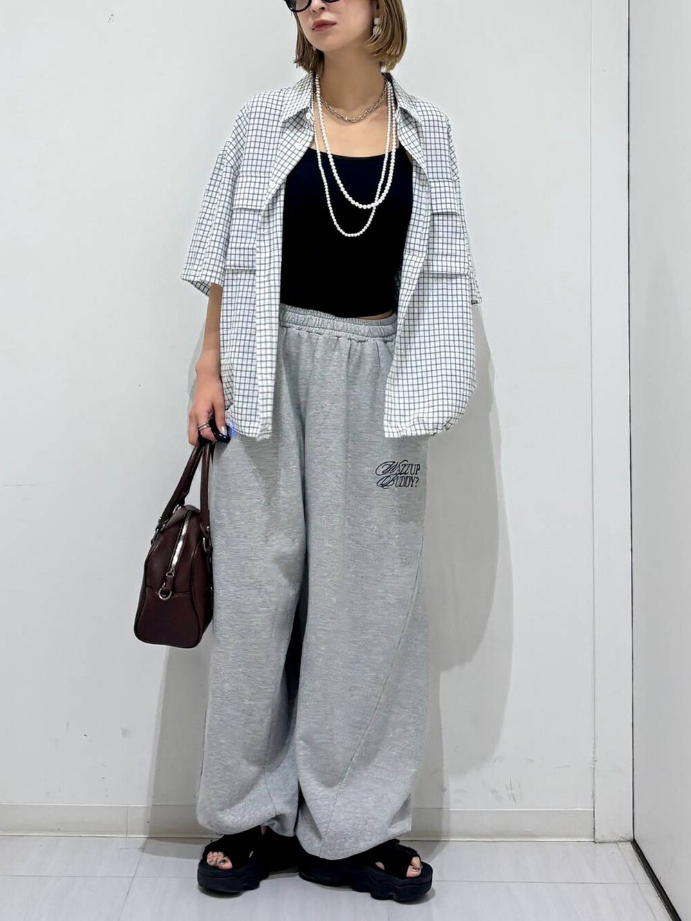 ブラウン系のショルダーバッグ、グレー系のスウェットパンツ、ホワイト系のシャツ/ブラウスを着用したレディースの夏コーディネートの6枚目の写真