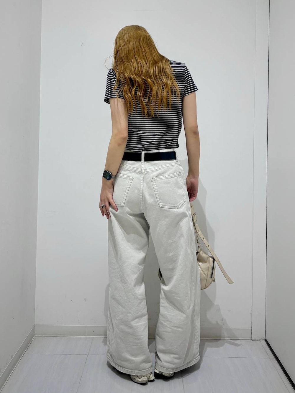 グレー系のデニムパンツ、ホワイト系のショルダーバッグ、ブラック系のTシャツ/カットソーを着用したレディースの春コーディネートの3枚目の写真