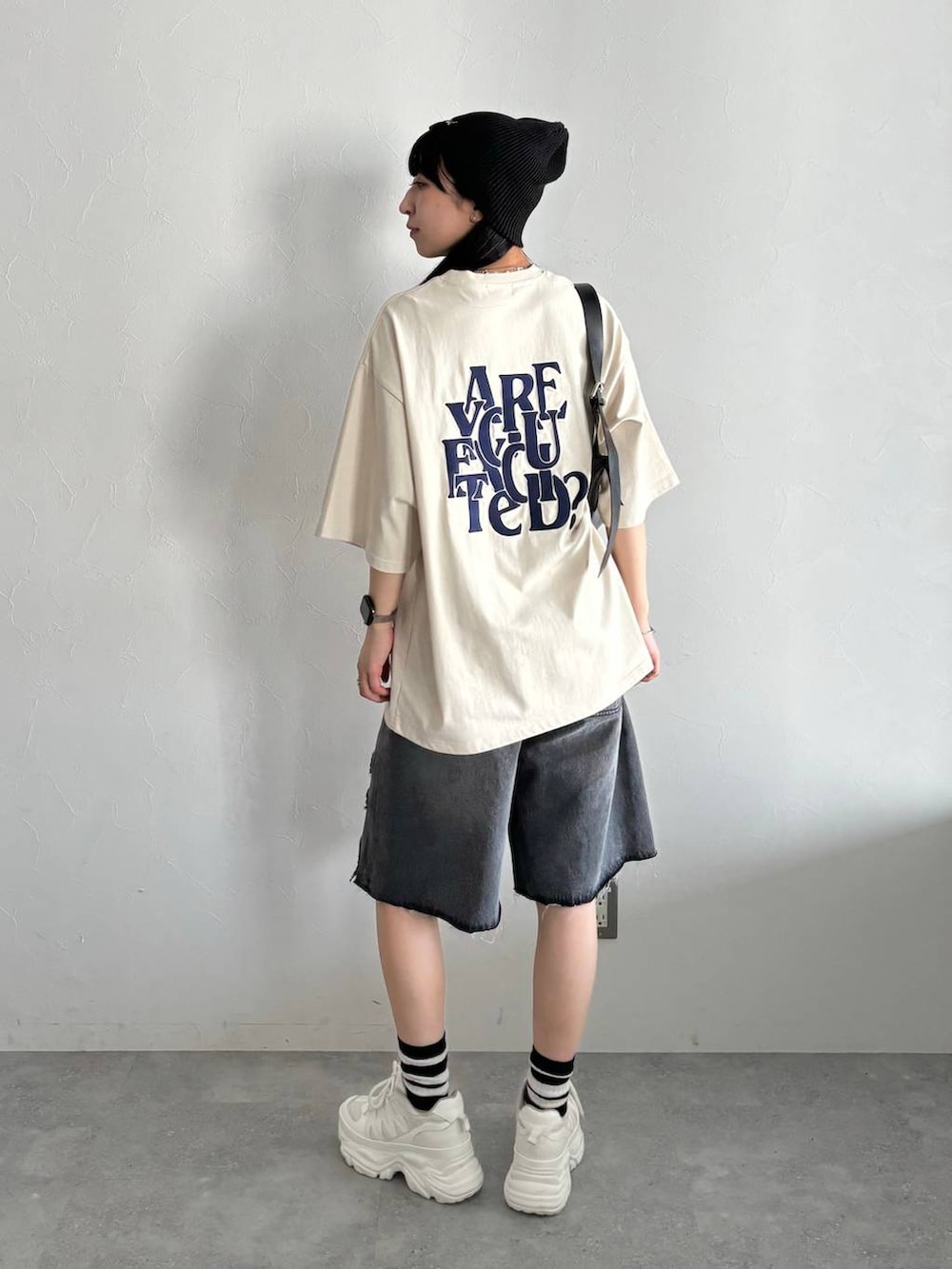 ホワイト系のスニーカー、ブラック系のショルダーバッグ、ブラック系のデニムパンツを着用したレディースの春コーディネートの3枚目の写真