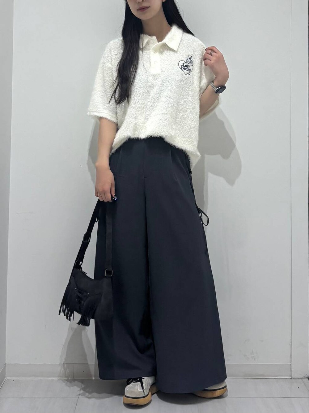 ブラック系のショルダーバッグ、グレー系のスラックス、ホワイト系のポロシャツを着用したレディースの春コーディネートの3枚目の写真