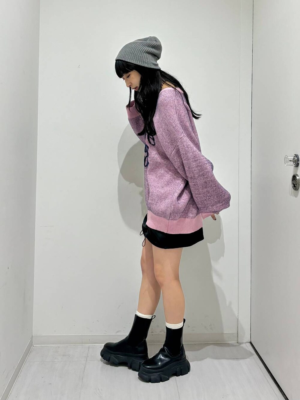 ブラック系のブーツ、ピンク系のニット/セーター、ホワイト系のショルダーバッグを着用したレディースの冬コーディネートの3枚目の写真