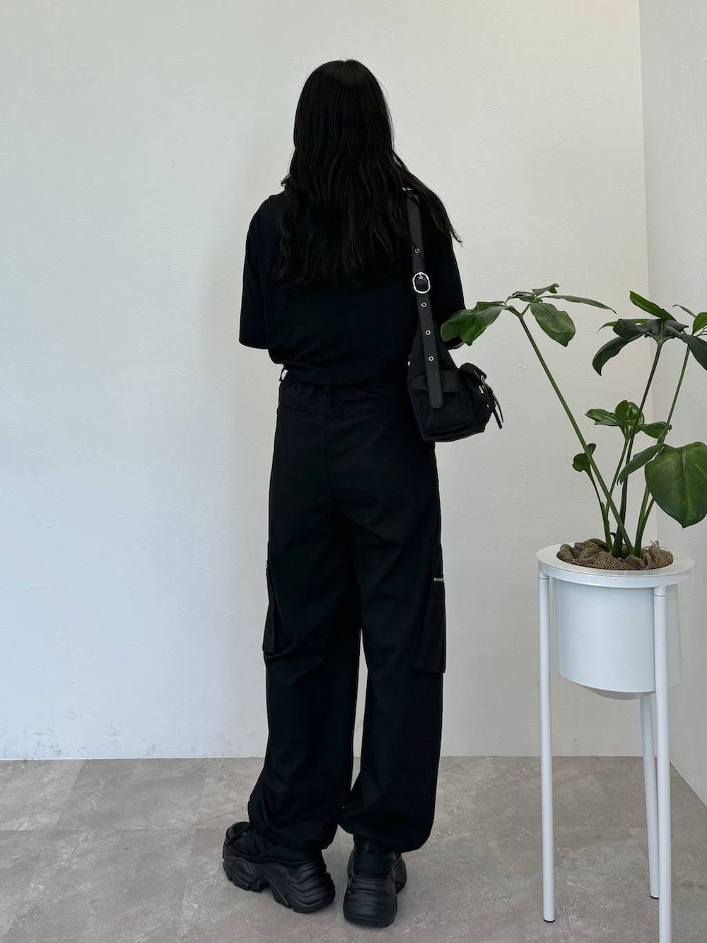 ブラック系のショルダーバッグ、ブラック系のスニーカー、ブラック系のスラックスを着用したレディースの春コーディネートの4枚目の写真