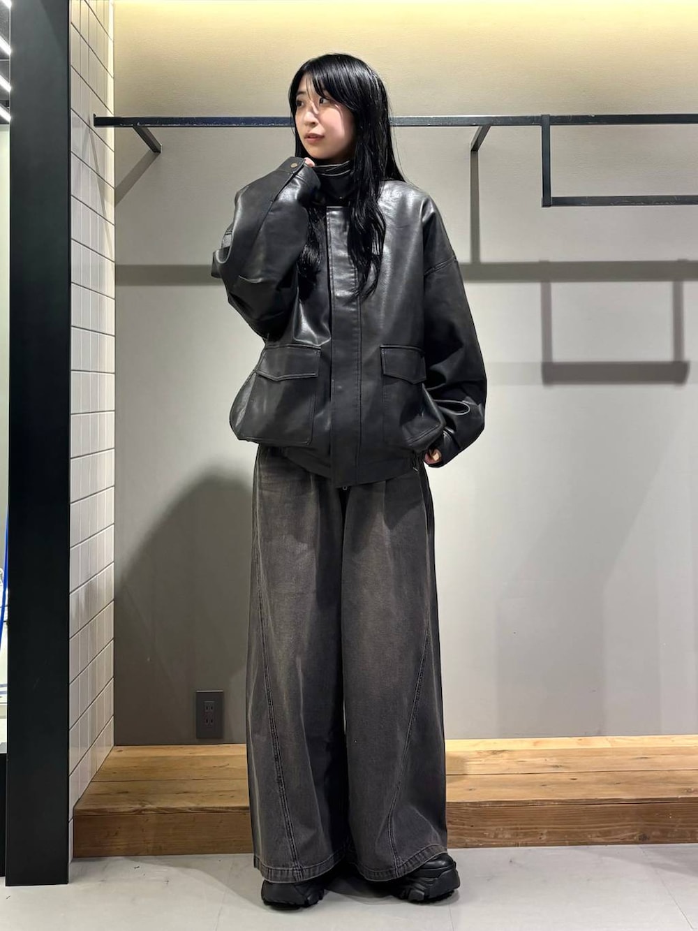 ブラック系のデニムパンツ、ブラック系のブルゾン、ブラック系のブーツを着用したレディースの秋コーディネートの2枚目の写真